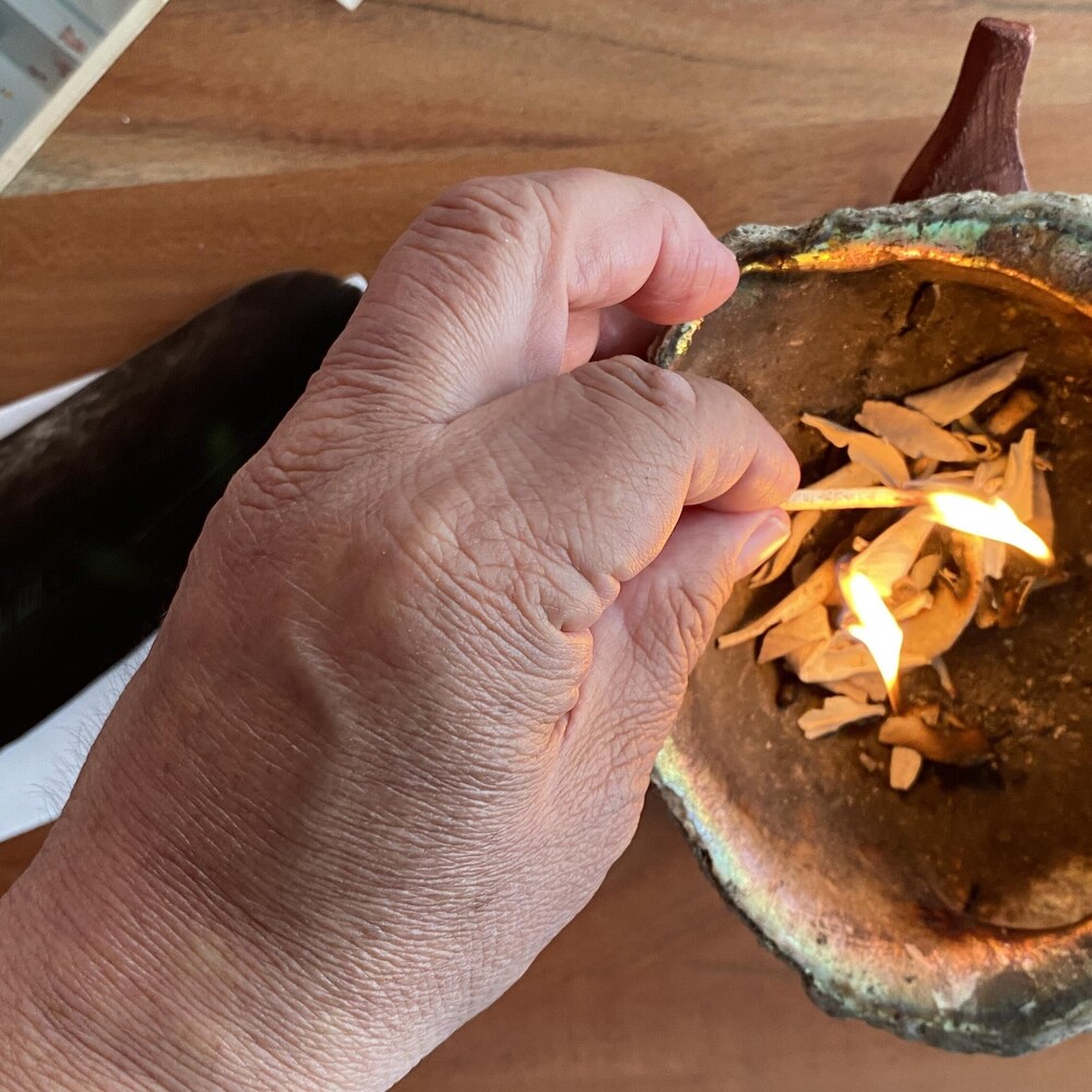 Une main qui allume un petit feu dans un coquillage