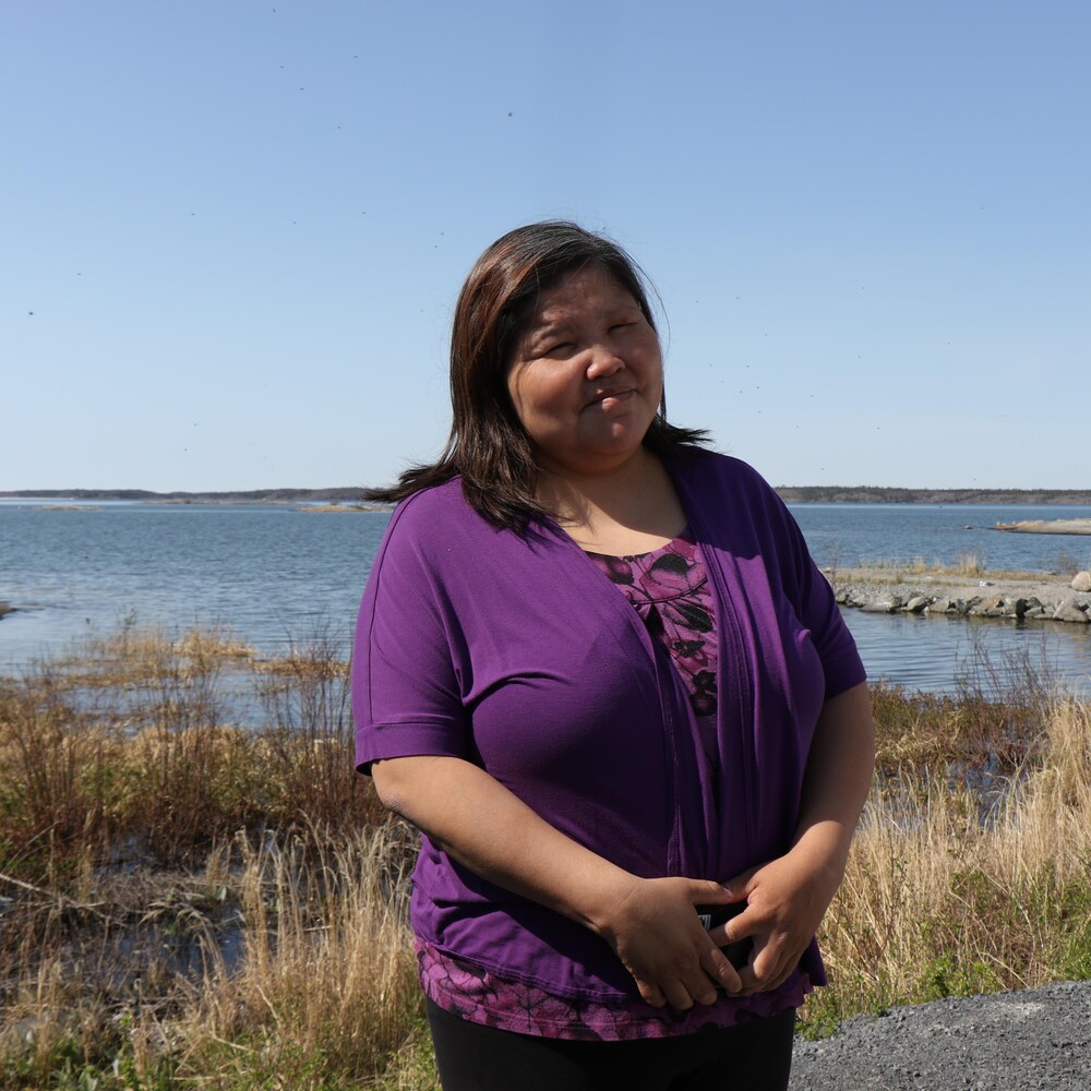 Une femme pose devant un lac.