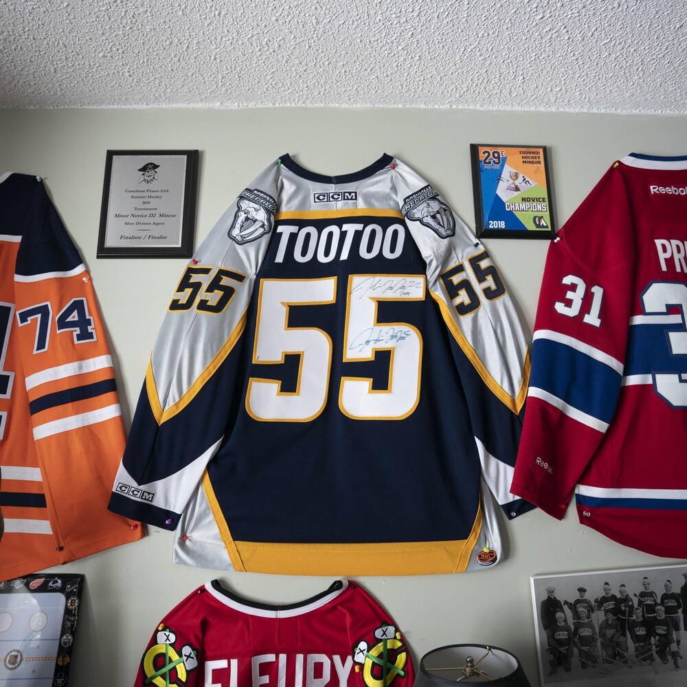 Des chandails de joueurs de hockey ornent les murs d'une chambre à coucher.