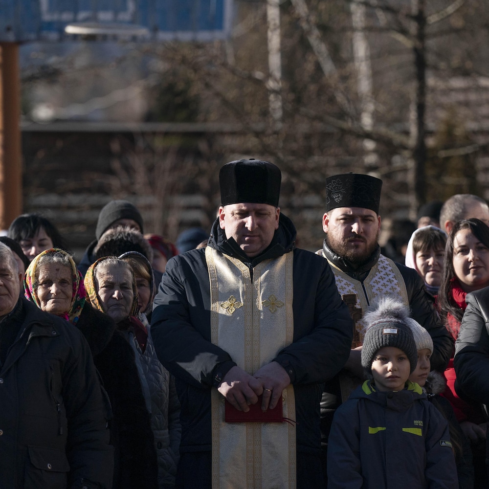 Le prêtre est entouré de ses fidèles devant son église.