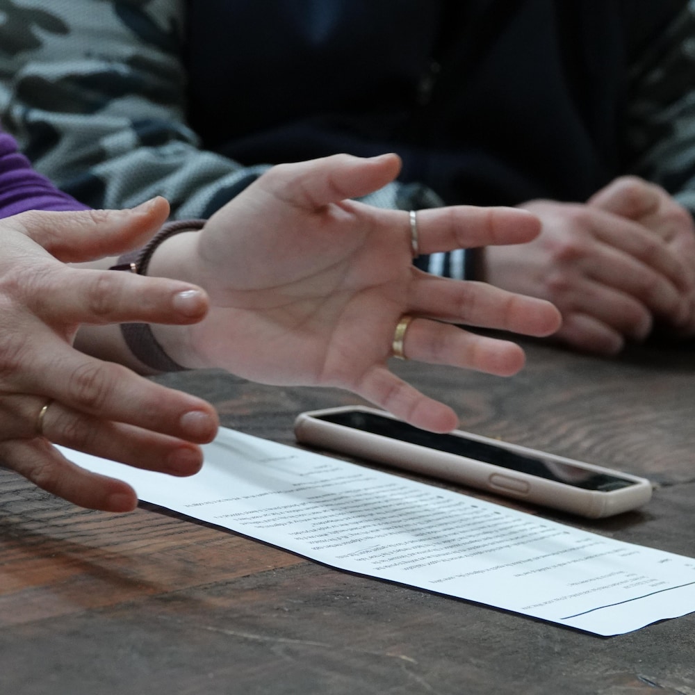 Des mains ouvertes au-dessus d'une feuille de papier déposée sur une table. 