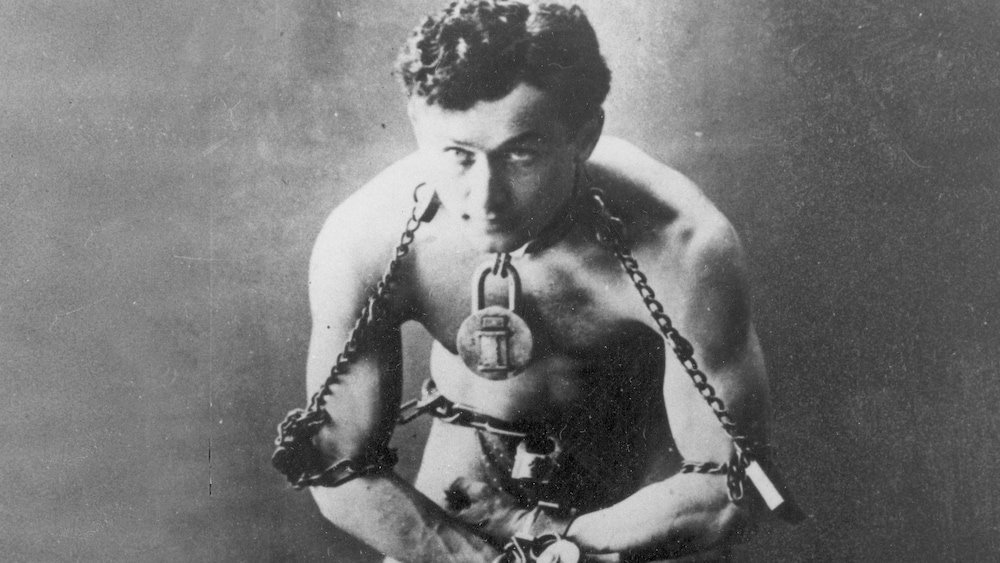 Photo de 1899 montrant l'illusionniste Harry Houdini en maillot, enchaîné et menotté comme s'il allait réaliser une évasion. 