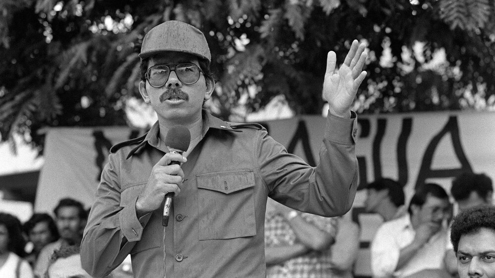 Daniel Ortega parle devant une foule, la main levée.