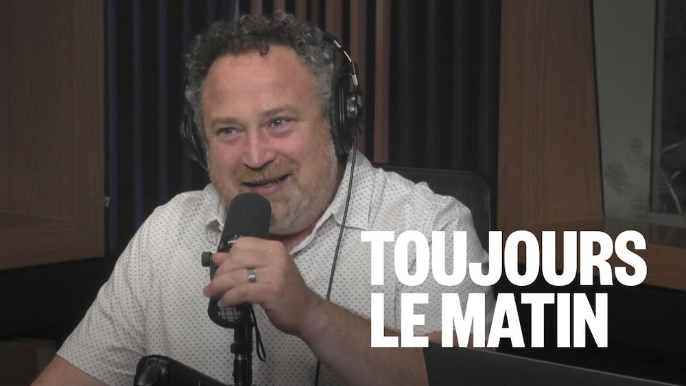 Jean Lamarche parle devant un micro en souriant. 