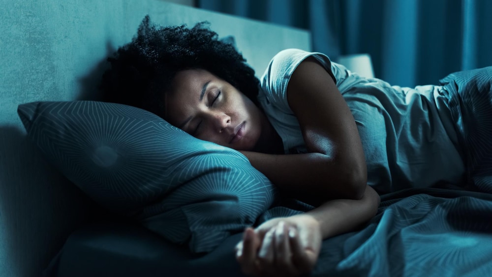 Une femme qui dort seule dans un lit.