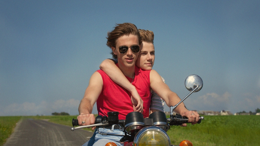 Les jeunes acteurs Benjamin Voisin et Félix Lefebvre sur une moto dans la campagne.
