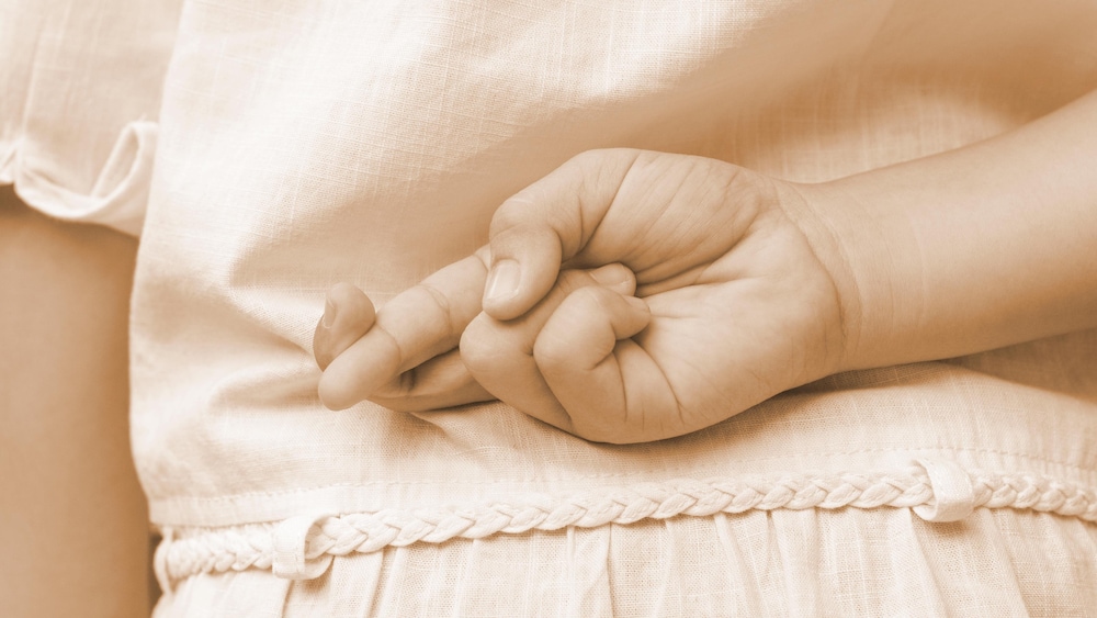Un enfant croise les doigts derrière son dos.