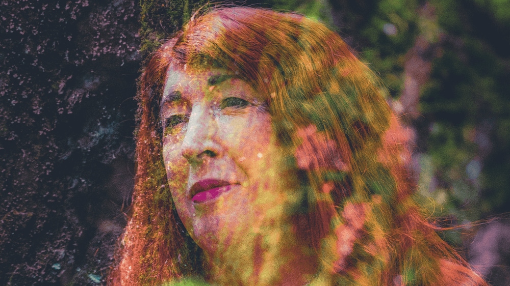 Photo artistique où le portrait d'une personne se confond avec la nature.