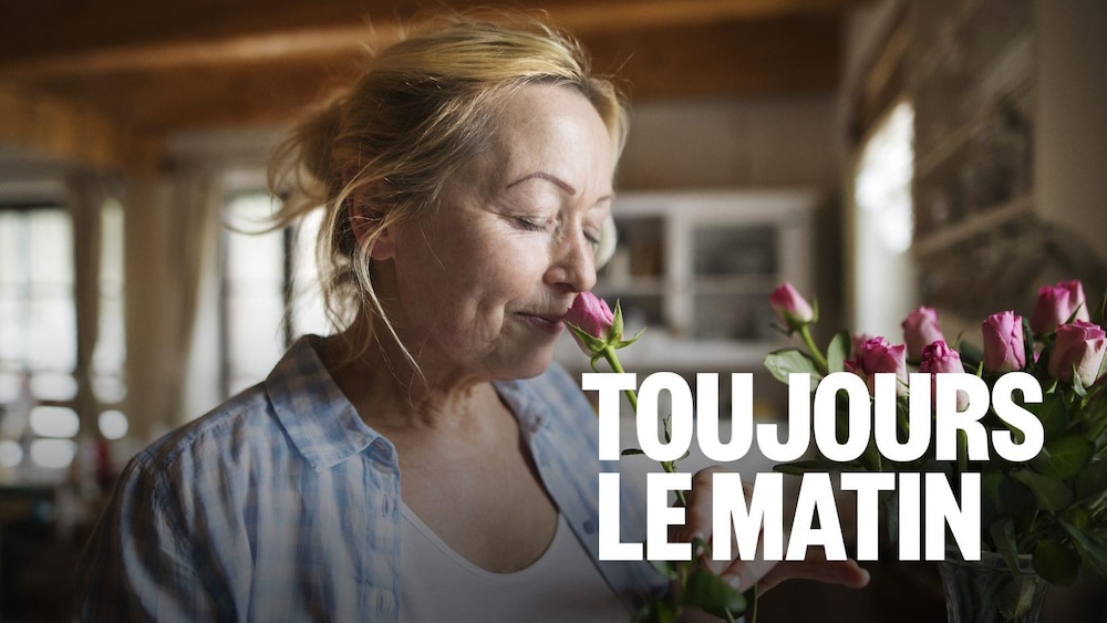 Une femme âgée sent une rose.