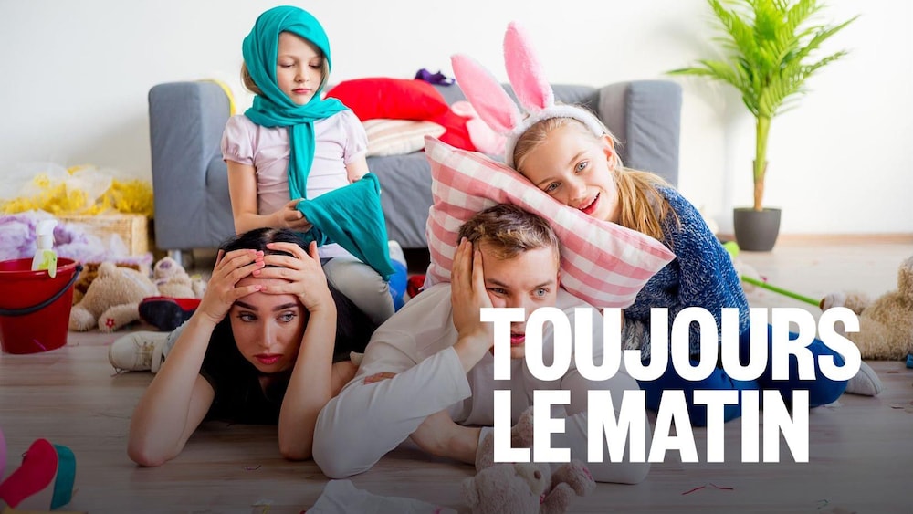 Des parents fatigués couchés sur le plancher, avec des enfants turbulents par dessus.