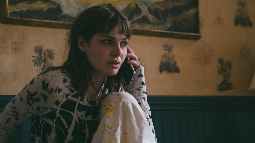 K-FILMS AMÉRIQUE Une fille pleure au téléphone assise dans un lit.