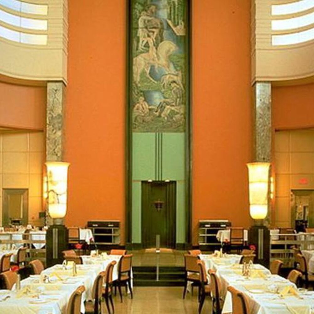 Une vaste salle contenant des chaises et des tables dans un décor de style Art déco.