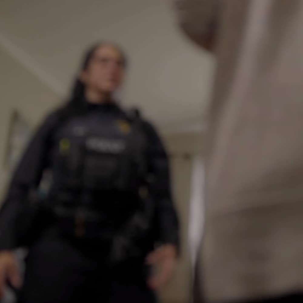 Capture d'écran d'une scène de la vidéo dans laquelle une policière écoute une victime. L'image est floutée. 