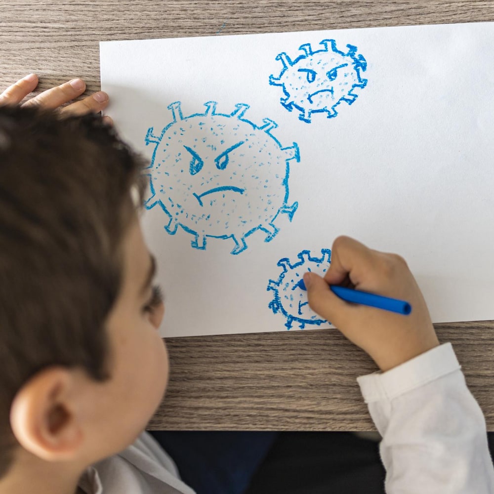 Un jeune garçon dessine un coronavirus.