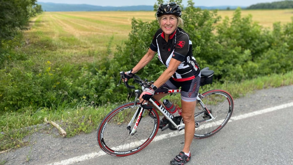Une cycliste sur un vélo près d'un champ.