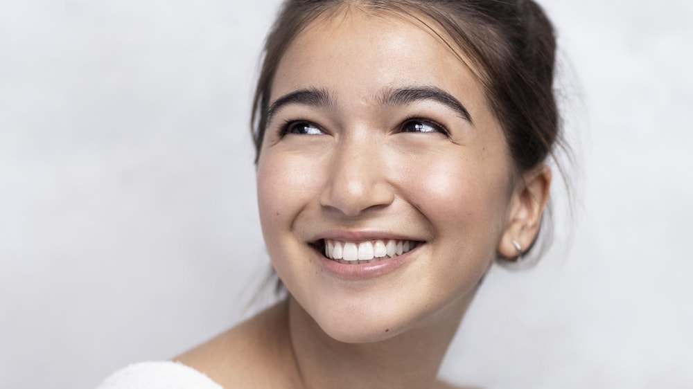 Une femme souriante qui pose en regardant vers la gauche.