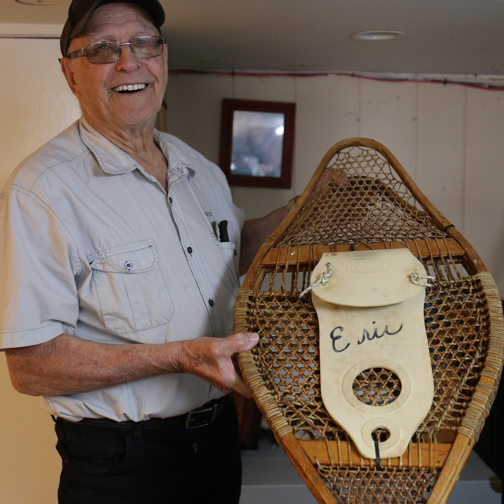 Eudore Fortin montre une raquette traditionnelle en souriant.