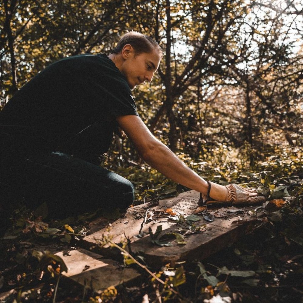 Steve Skafte balaie les feuilles de la main qui se trouvent sur pierre tombale.
