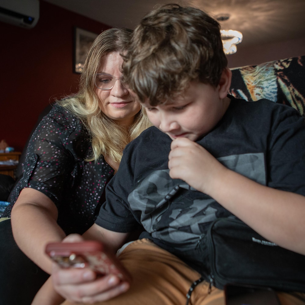 Roland et sa mère Tricia Latimer vérifient la qualité de l’air sur leur téléphone à Gold River, sur l'Île de Vancouver, le 29 novembre 2025.
