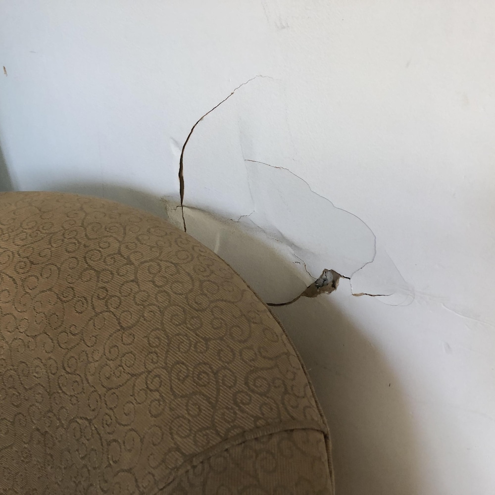 Un trou dans un mur, derrière un fauteuil.