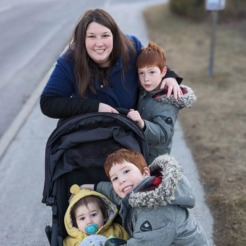 Une mère et ses trois enfants enlassés autour d'une poussette