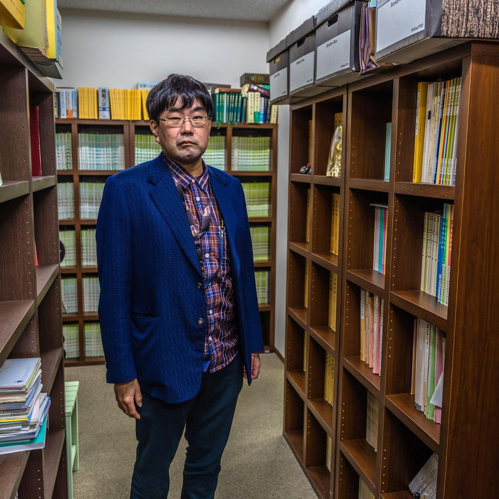 Takashi Yamaguchi entouré de bibliothèques.