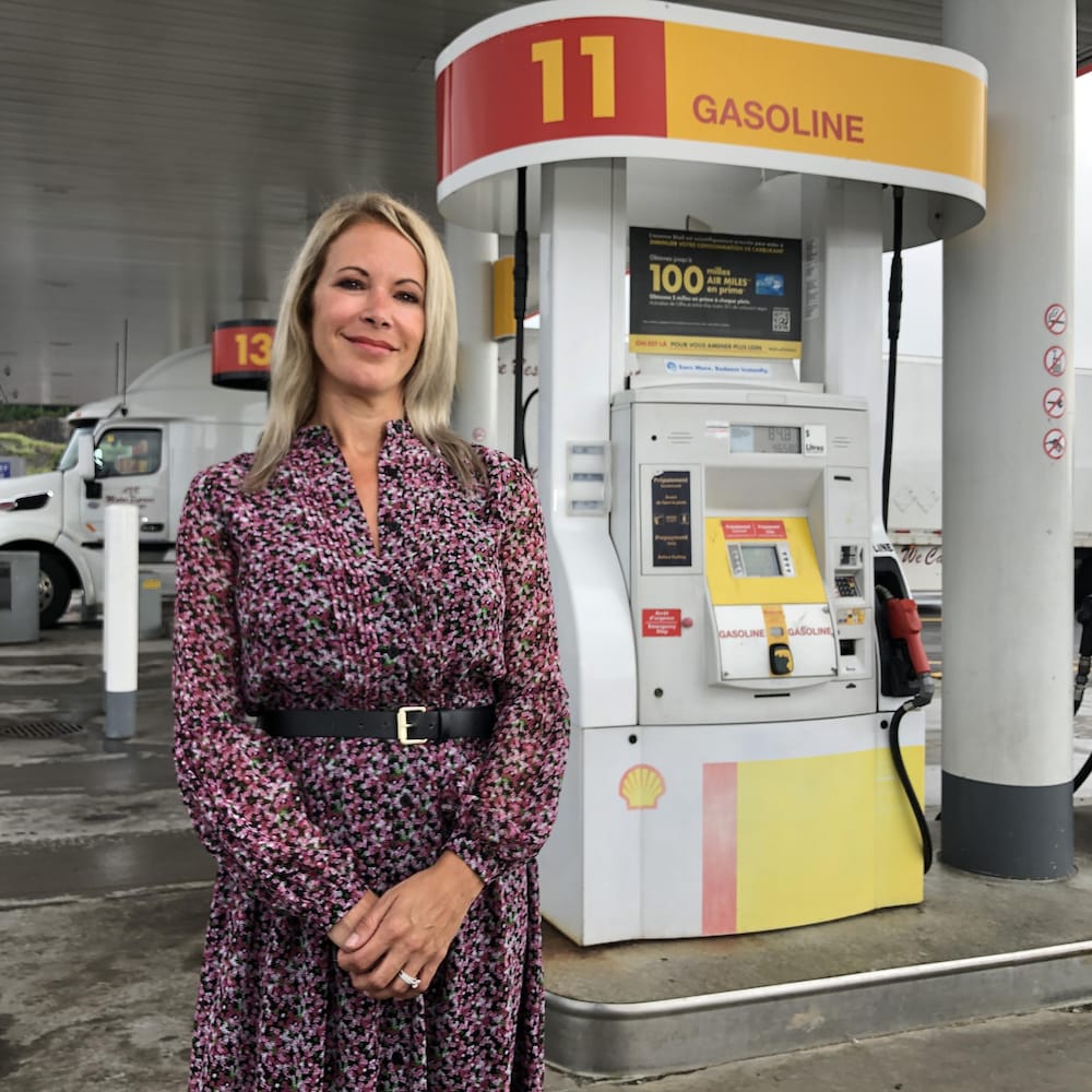 Une femme devant une pompe à essence.