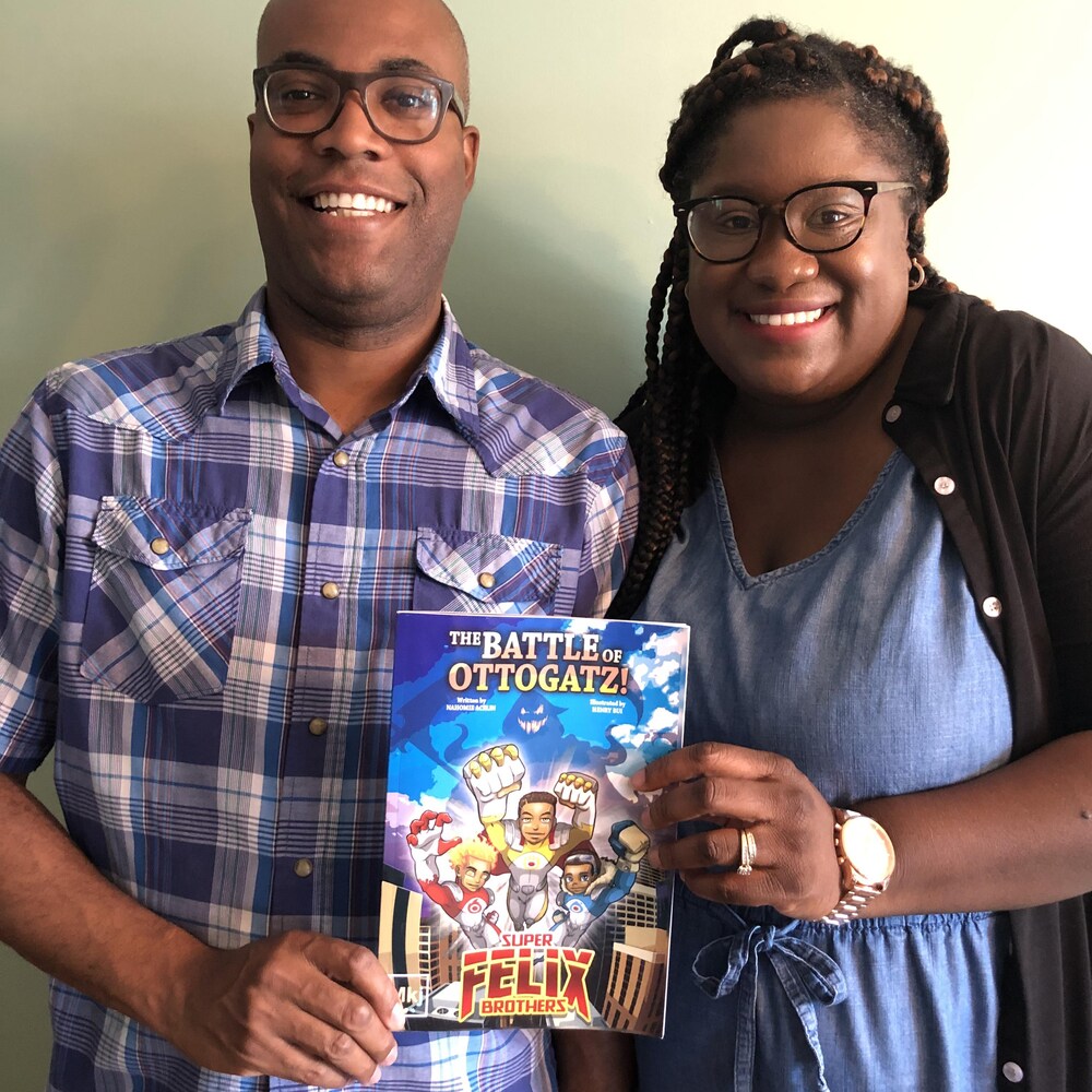Un couple souriant tenant une bande dessinée.