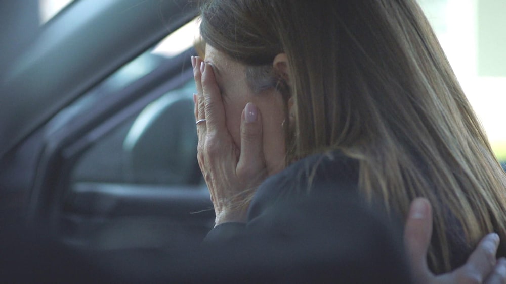 Une femme qui cache son visage dans ses mains.