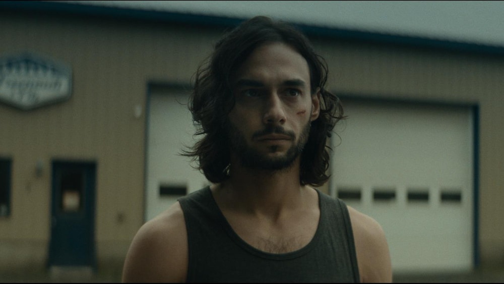 Sphere Films Un jeune homme devant un garage.