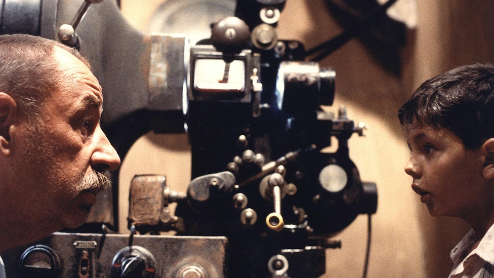 Un homme et un garçon devant un projecteur de cinéma.