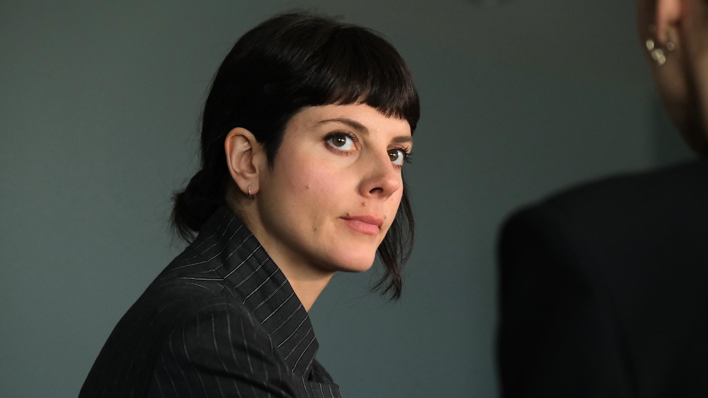 Les Productions Sovimage / Bertrand Calmeau Une femme de profil regarde attentivement une autre femme qu'on voit de dos.