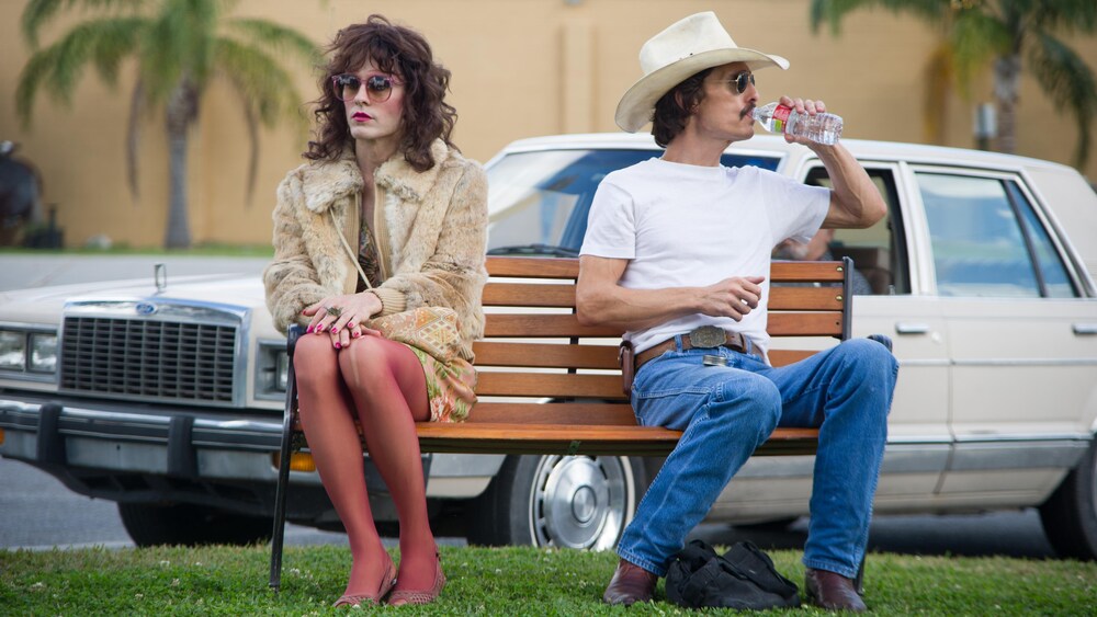 Un travesti et un homme en tenue de cow-boy assis sur un banc