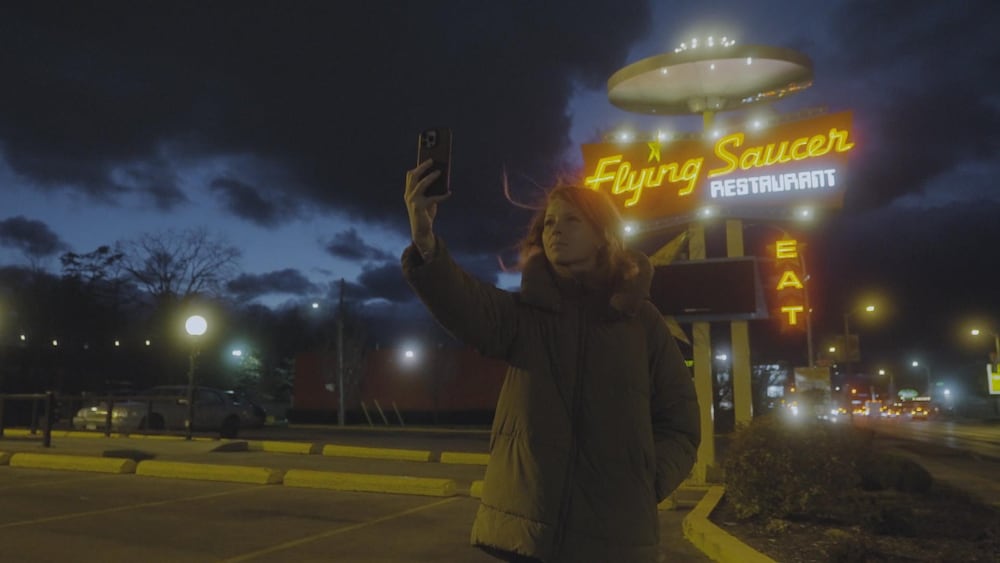L’animatrice Mélissa Offner se prend en photo devant l'enseigne du restaurant Flying Saucer.