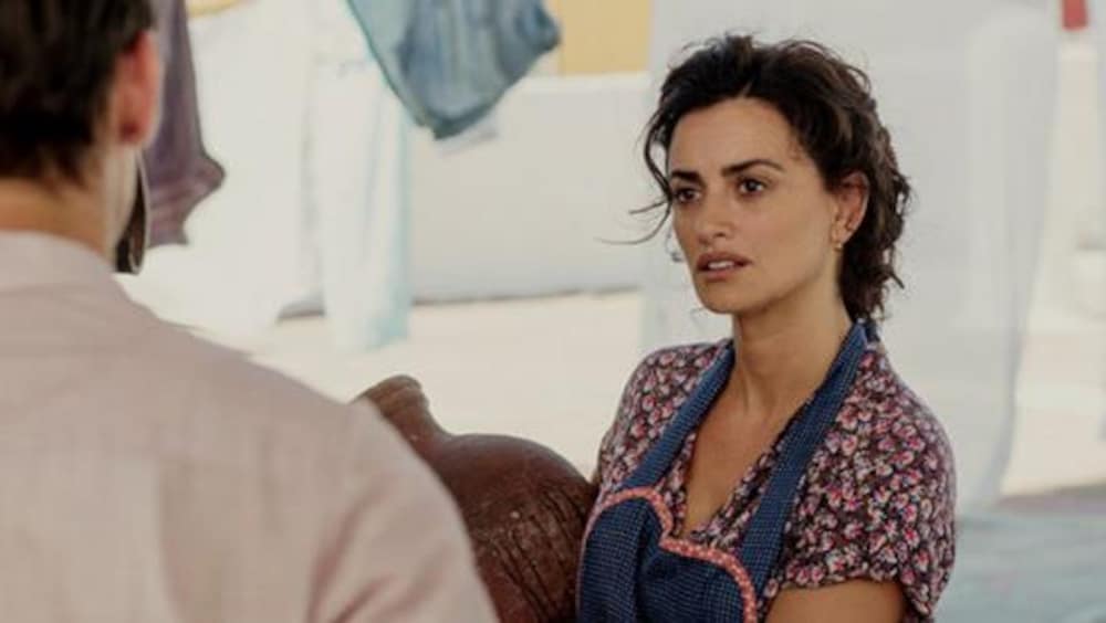 Une femme en tablier, regarde un homme en face d'elle.