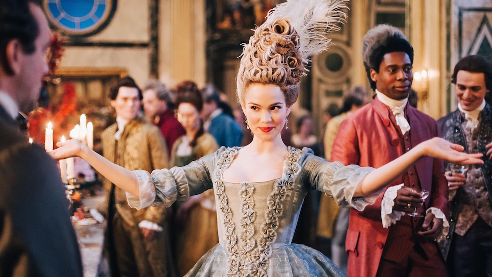 Emilia Schüle dans le rôle de Marie Antoinette dans un grand bal royal.