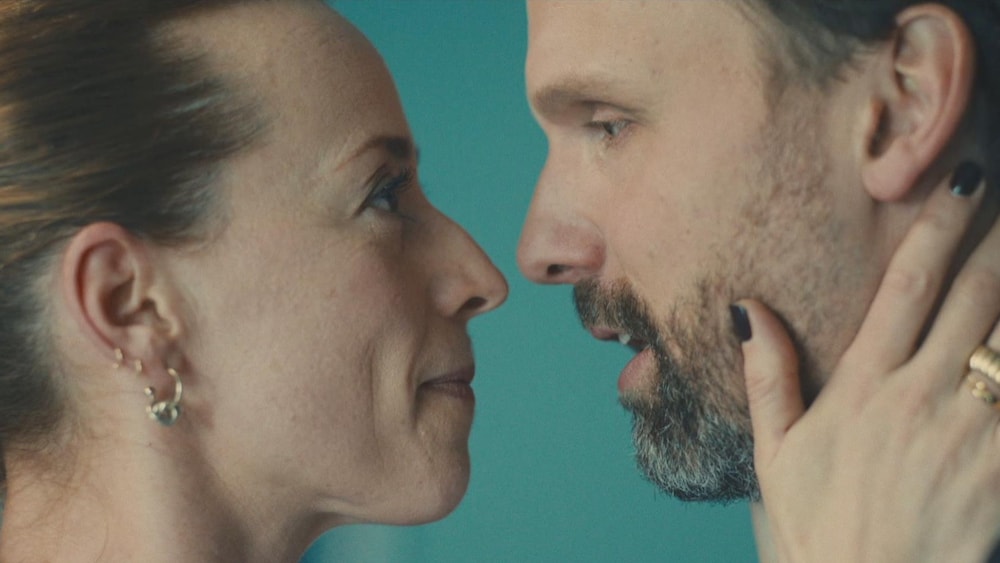 Un gros plan du visage d'une femme et d'un homme. La femme tient la tête de l'homme entre ses mains.