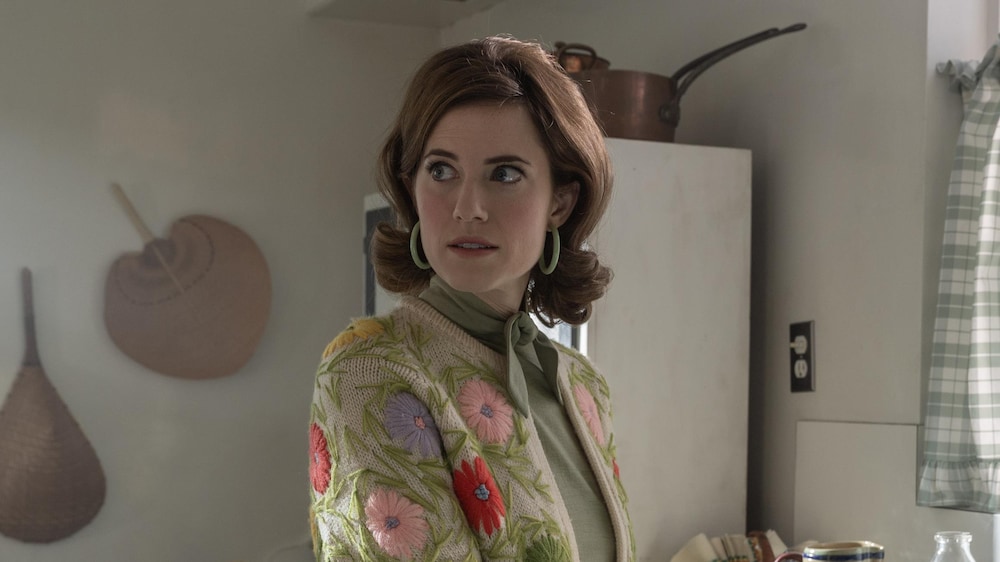 Lucy Smith se tient dans une cuisine et regarde derrière elle. 