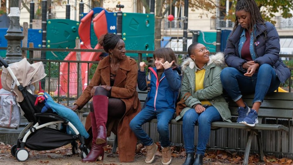K-Films Amérique Trois femmes et un enfant assis sur un banc de parc.
