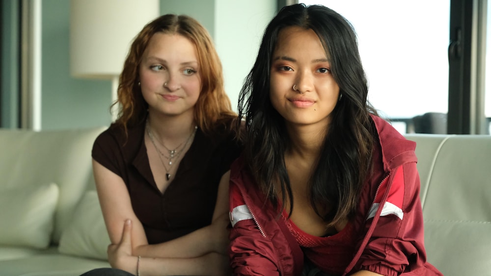 Deux jeunes femmes assises côte à côte sur un divan.