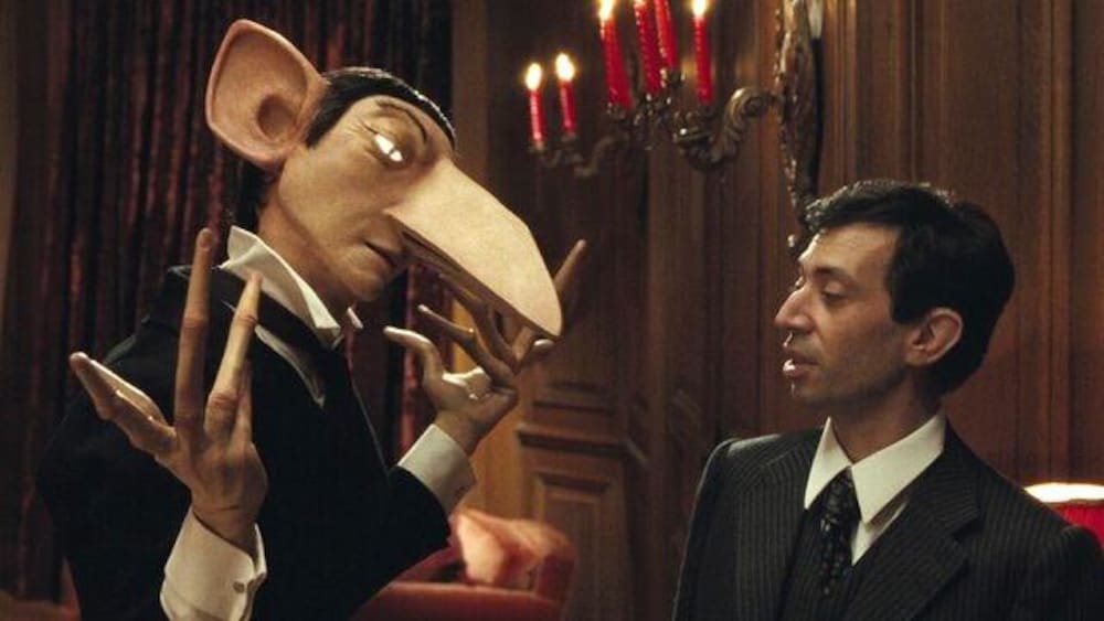 One World Films Un homme (Eric Elmosnino) en complet look à une marionnette lui ressemblant.