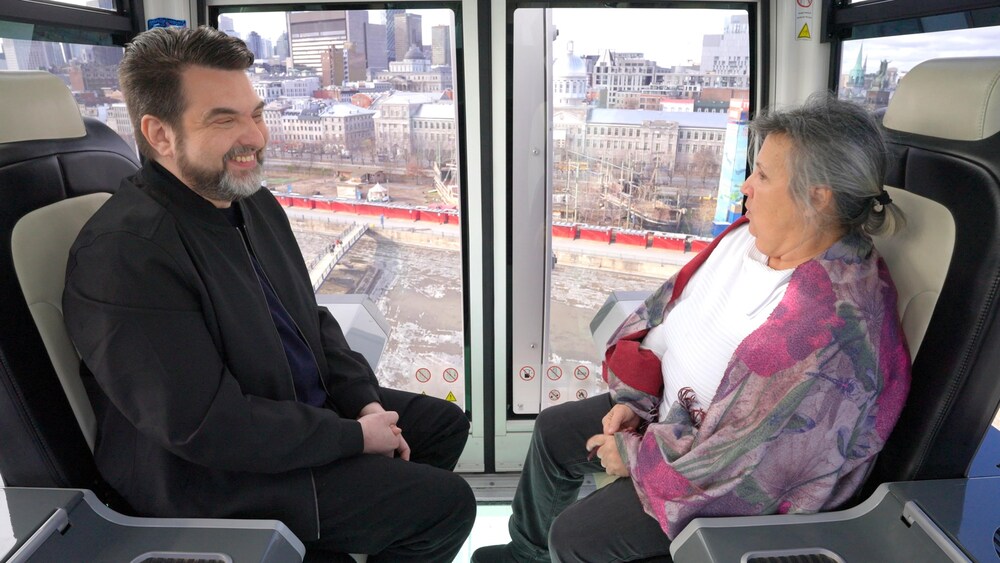Hyperzoom Les deux personnes sont assises et dans les airs avec des bâtiments de Montréal à l'arrière plan.