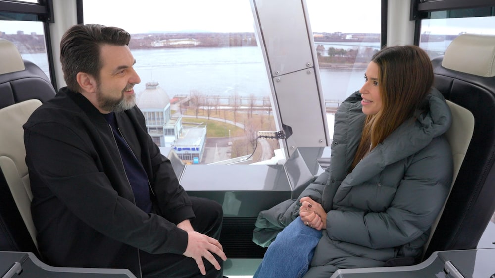 Hyperzoom Les deux personnes sont assises dans la cabine et dans les airs avec le fleuve Saint-Laurent à l'arrière plan.