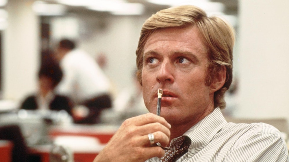 Warner Bros. Un homme (Robert Redford), un crayon devant la bouche.