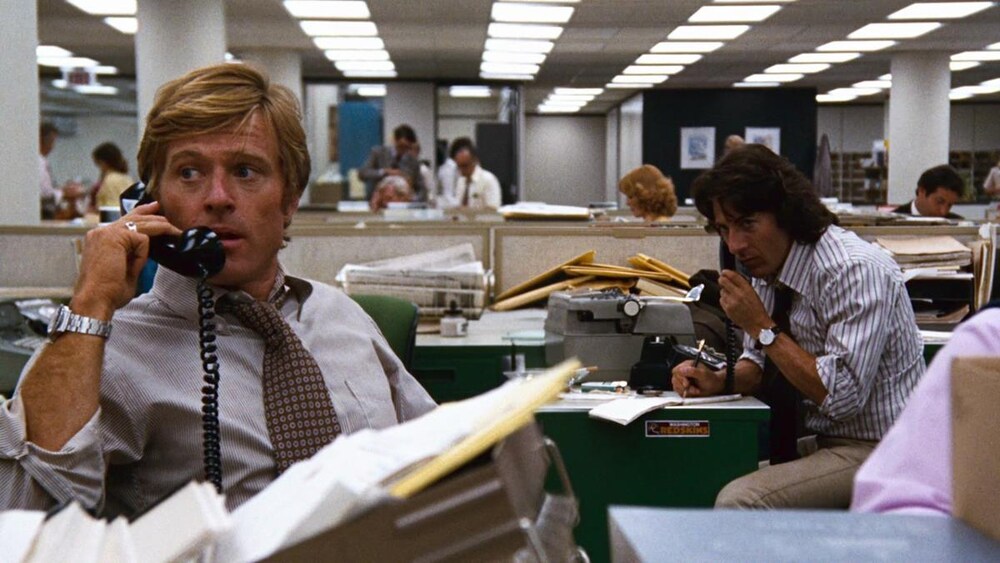 Dans un bureau ouvert, deux hommes (Robert Redford et Dustin Hoffman) au téléphone.