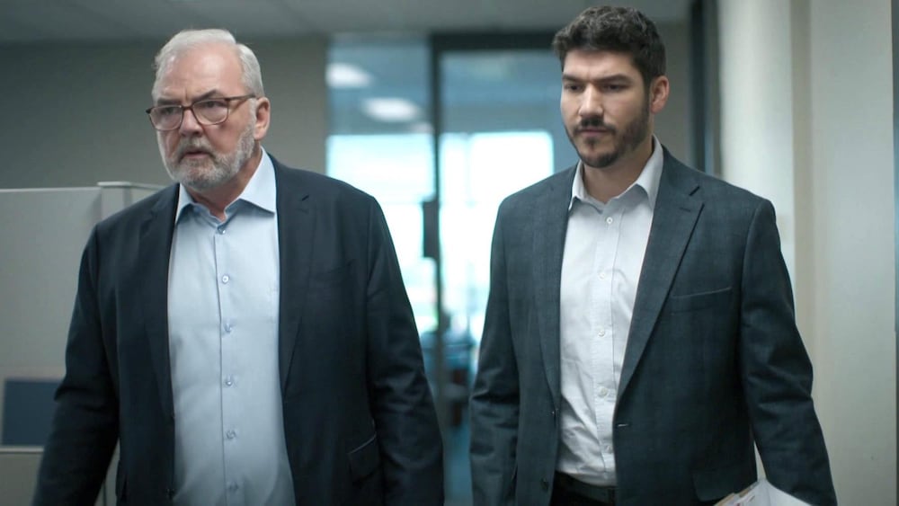 Aetios Productions Deux hommes qui marchent, l'un à côté de l'autre, dans un bureau.