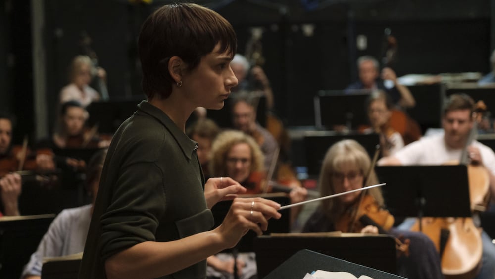 Une femme (Sophie Desmarais) en train de diriger un orchestre.