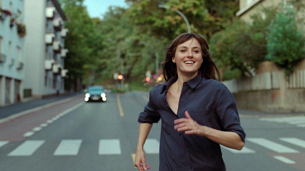 MK2 Mile-End Une femme (Renate Reinsve) court dans la rue en souriant.