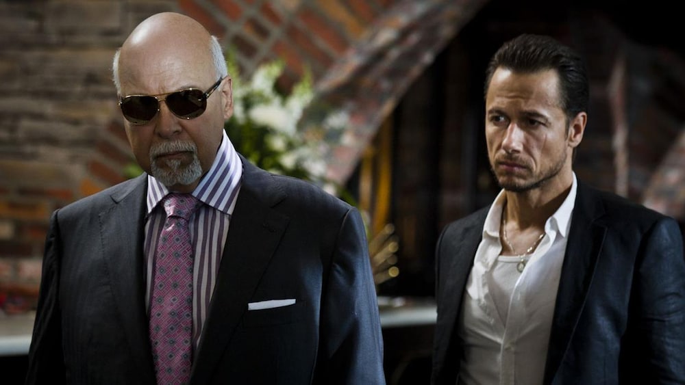 Alliance Vivafilm Deux hommes en costumes dont un porte des lunettes noires.
