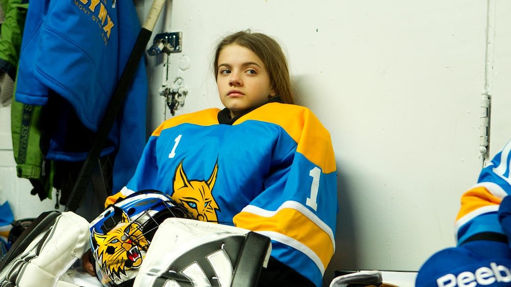 Les films Séville Une jeune fille en équipement de goal assise sur un banc.